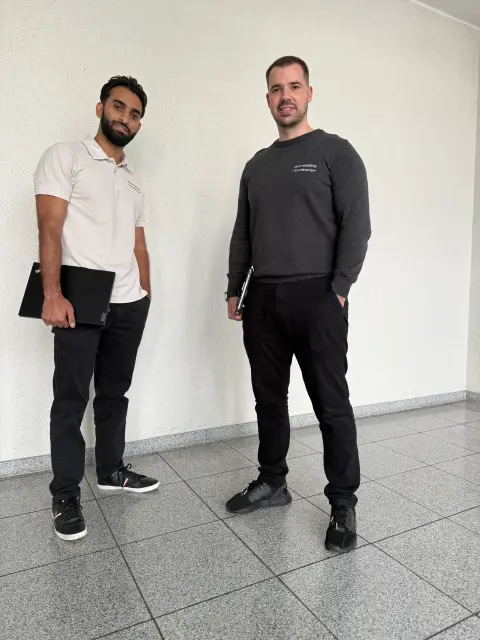 Zwei Mitarbeiter von netzwerkfähig stehen mit Notebooks im Foyer des Bürogebäudes