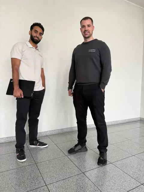 Zwei Mitarbeiter von netzwerkfähig mit Notebooks im Treppenhaus des Bürogebäudes