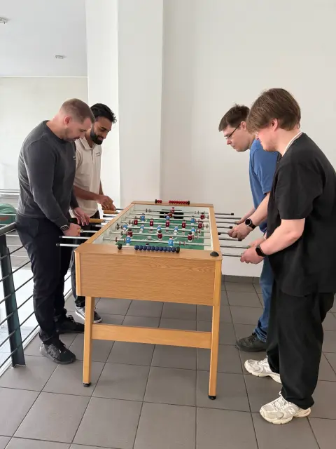 Vier Mitarbeiter von netzwerkfähig am Kickertisch im Büro