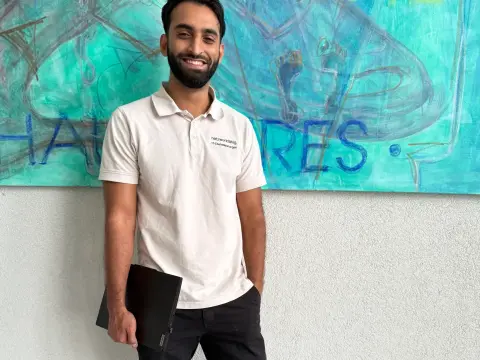 Mitarbeiter von netzwerkfähig mit Notebook vor einem Wandgemälde im Foyer