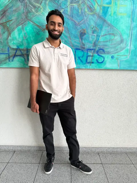 Mitarbeiter von netzwerkfähig mit Notebook vor einem Wandgemälde im Foyer