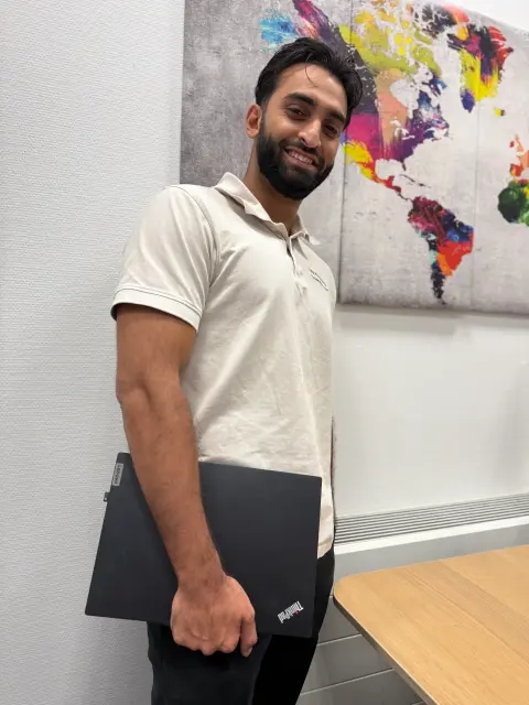 Mitarbeiter von netzwerkfähig mit Notebook vor einer Weltkarte im Büro
