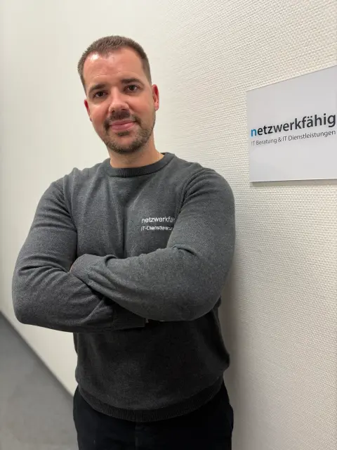 Mitarbeiter von netzwerkfähig am Eingang zum Büro mit dem netzwerkfähig-Schild