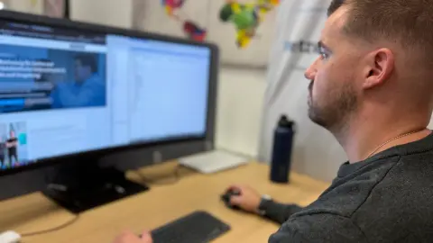 Mitarbeiter von netzwerkfähig am Desktop-Arbeitsplatz mit großem Monitor