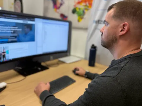 Mitarbeiter von netzwerkfähig am Desktop-Arbeitsplatz mit großem Monitor