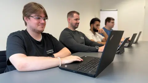 Vier Mitarbeiter von netzwerkfähig arbeiten an Notebooks im Besprechungsraum