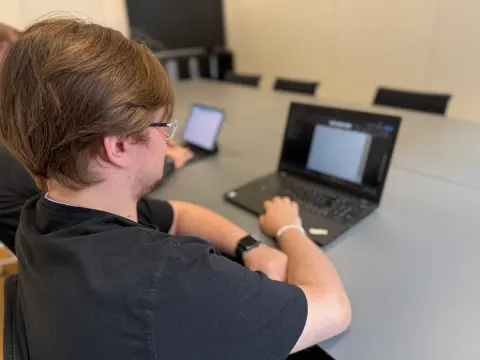 Blick über die Schulter auf ein Notebook am Besprechungstisch