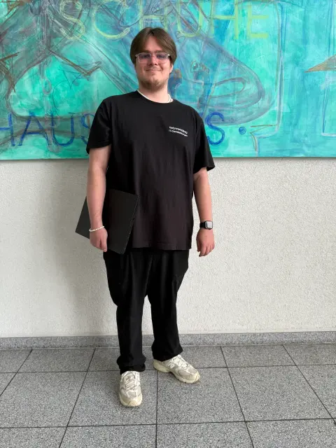 Mitarbeiter von netzwerkfähig mit Notebook vor einem Wandgemälde im Foyer