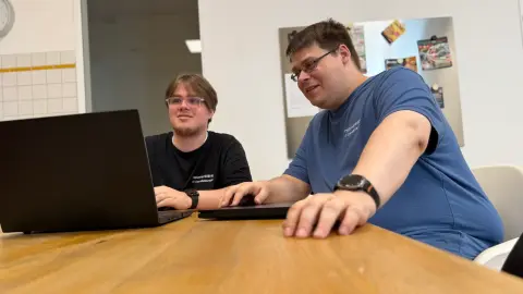 Zwei Mitarbeiter von netzwerkfähig arbeiten am Notebook in der Büroküche