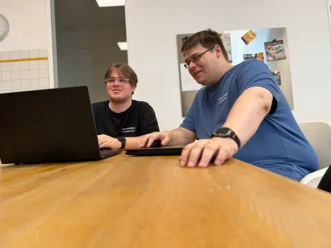 Zwei Mitarbeiter von netzwerkfähig arbeiten am Notebook in der Büroküche