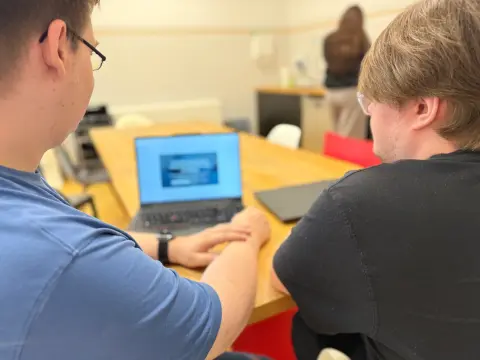 Zwei Mitarbeiter von netzwerkfähig am Notebook in der Büroküche