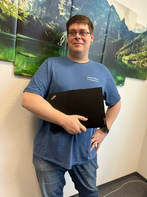 Mitarbeiter von netzwerkfähig mit Notebook vor einem Landschaftsbild im Büro