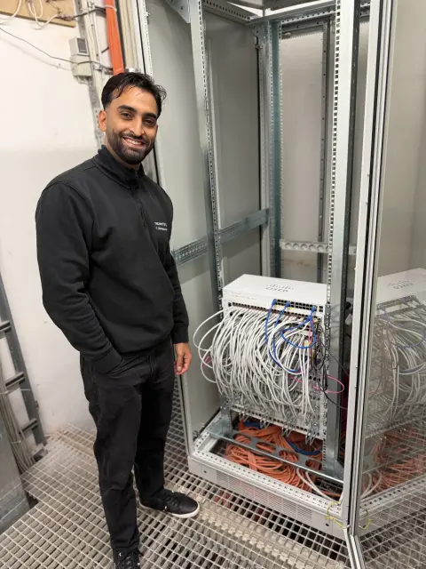 Mitarbeiter von netzwerkfähig vor einem Netzwerkschrank mit Switches und Patchkabeln