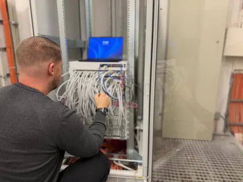Mitarbeiter von netzwerkfähig patcht Netzwerkkabel im Netzwerkschrank