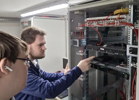 Zwei Mitarbeiter von netzwerkfähig prüfen Geräte im Serverrack