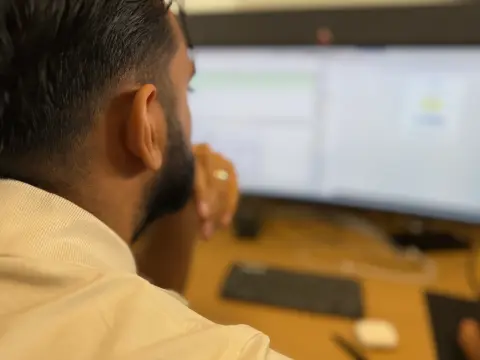 Mitarbeiter von netzwerkfähig arbeitet an zwei Monitoren, von hinten fotografiert