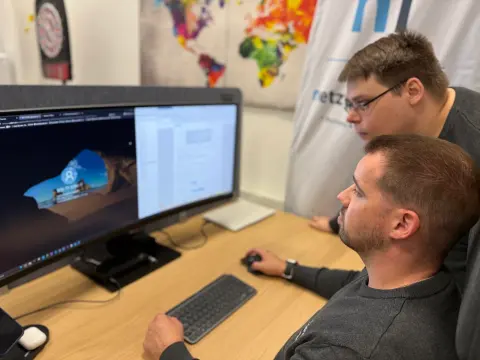 Zwei Mitarbeiter besprechen sich am Arbeitsplatz vor dem Monitor