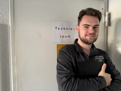 Mitarbeiter von netzwerkfähig mit Notebook vor dem Technikraum