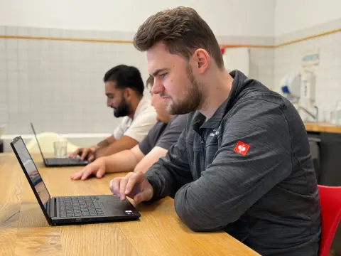 Zwei Mitarbeiter arbeiten gemeinsam am Notebook im Aufenthaltsraum