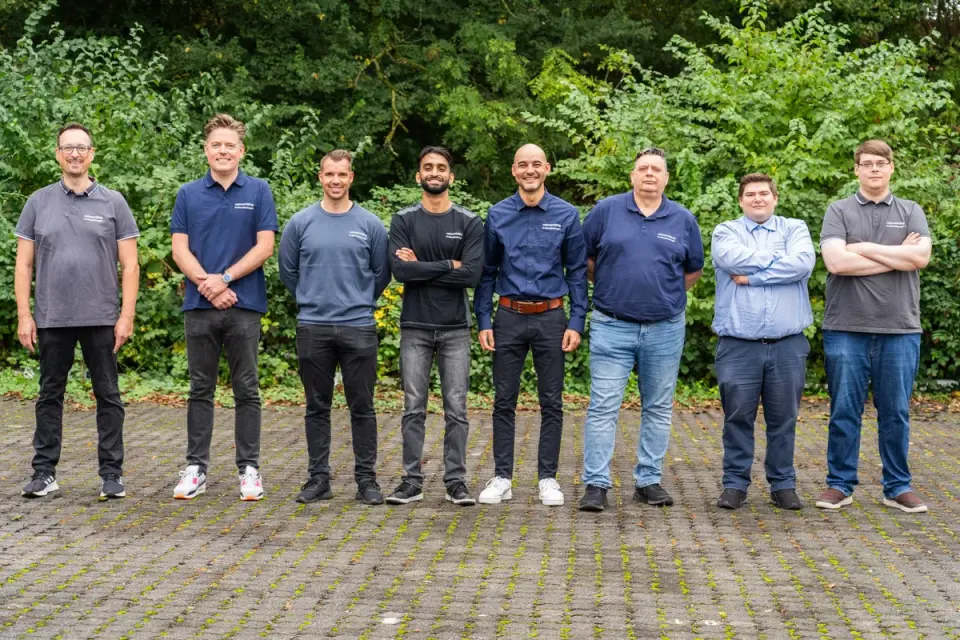 Das achtköpfige Team von netzwerkfähig im Freien vor grünen Büschen